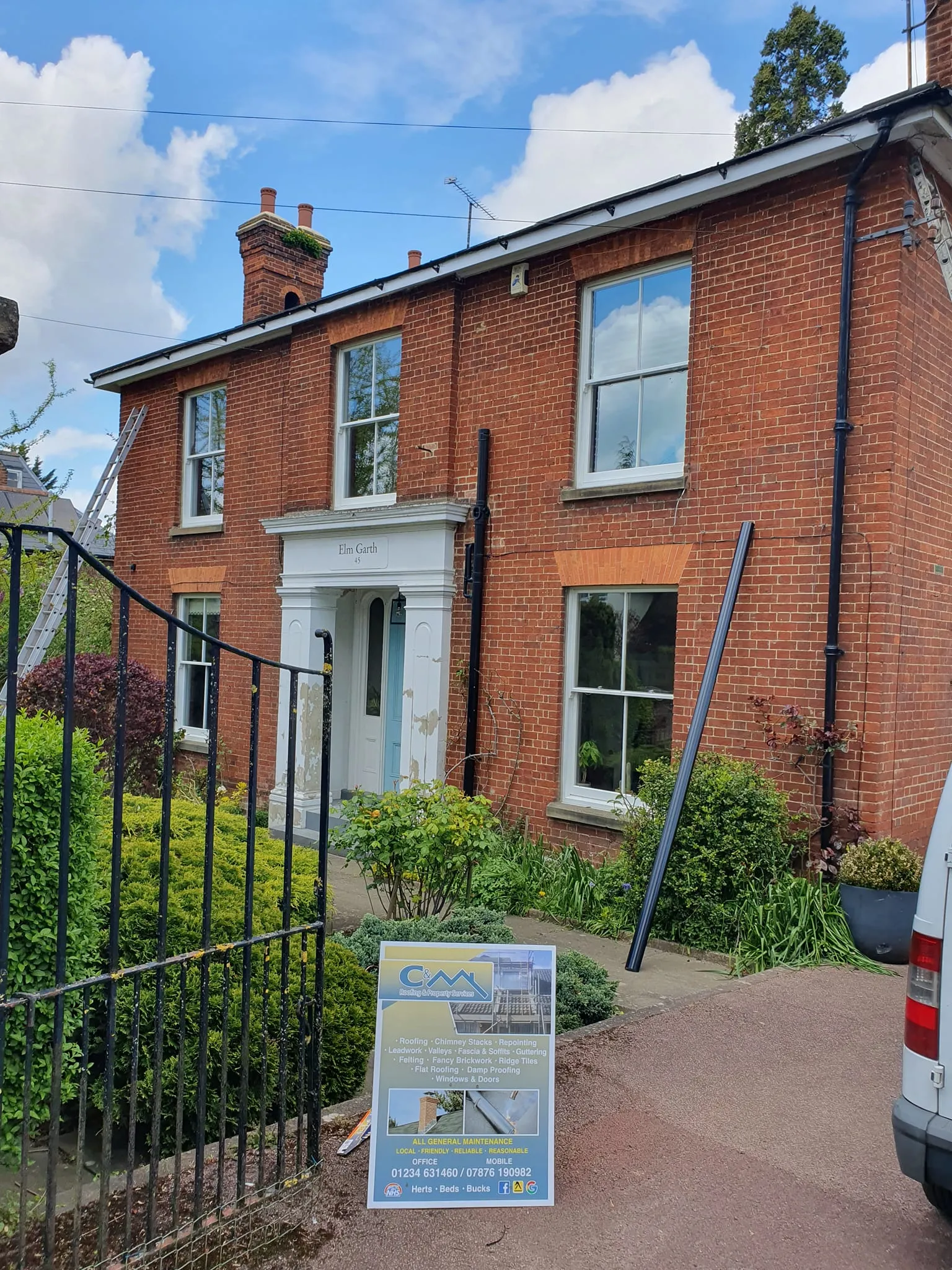 A sign is in front of a brick house.