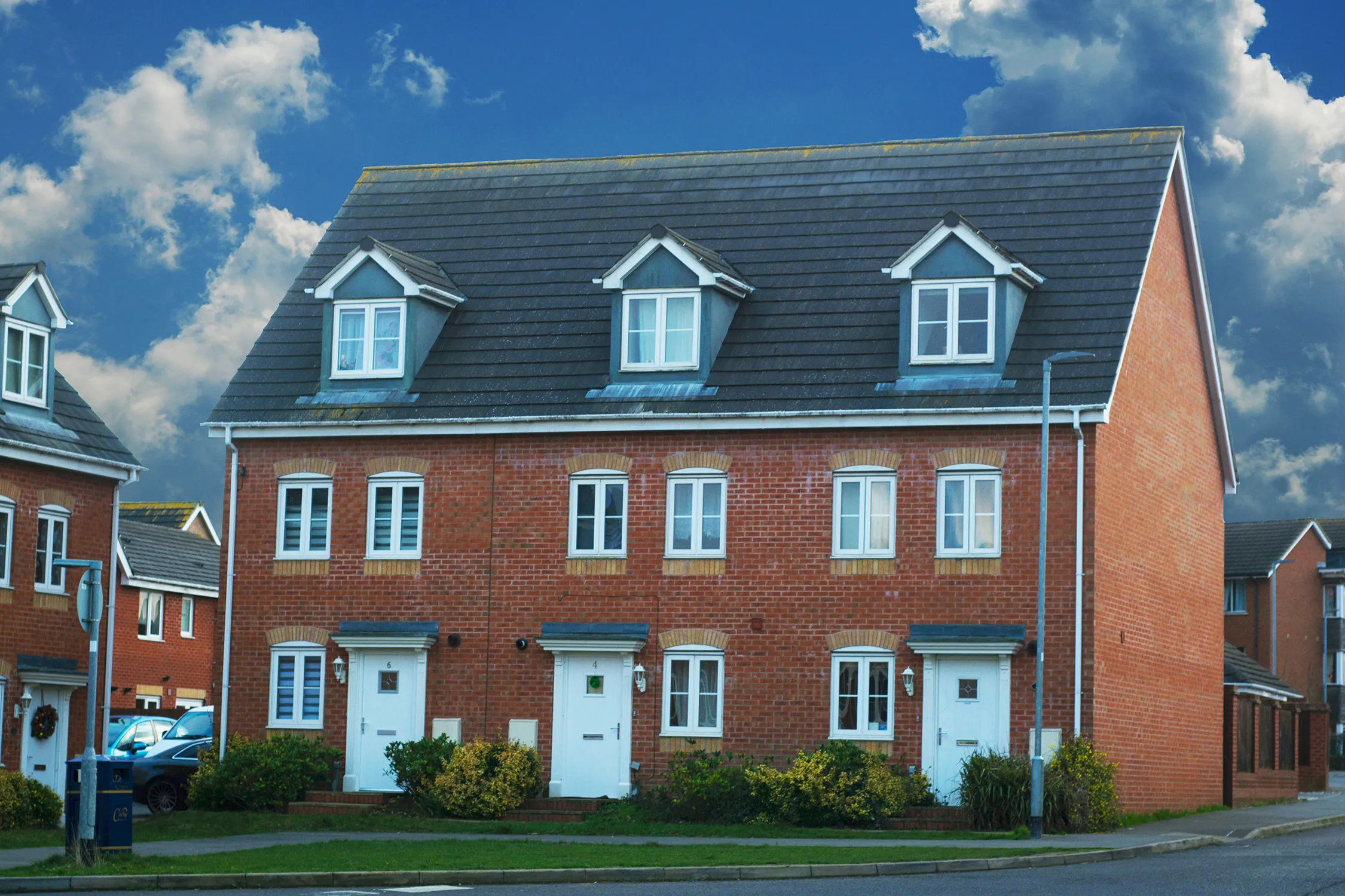 A row of red brick houses with white doors.